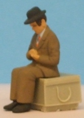 Omen - Sitting man, wearing a trilby hat, looking down