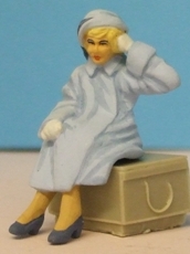 Omen - Seated woman wearing a loose-fitting coat
